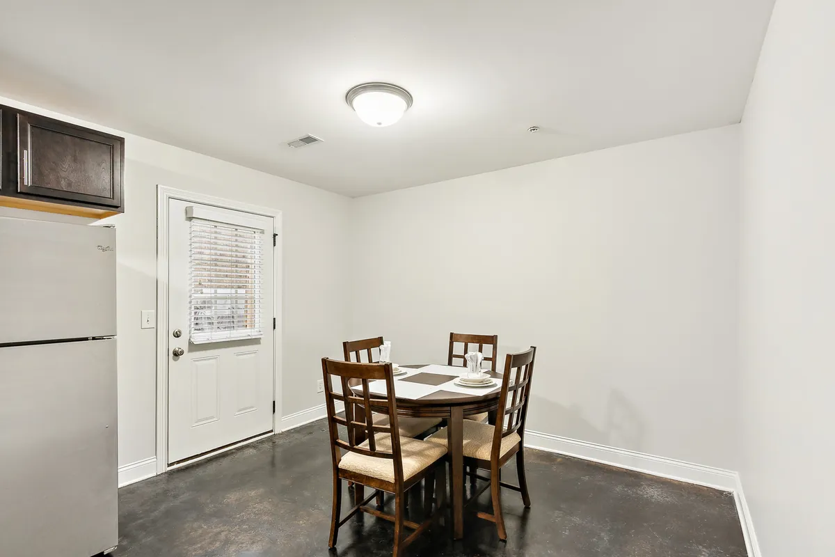 A view of the interior entryway leading into an open, spacious main level with a dining table and comfortable chairs. The door is a focal point, emphasizing the direct transition from the private exterior into a welcoming, thoughtfully arranged entry space.