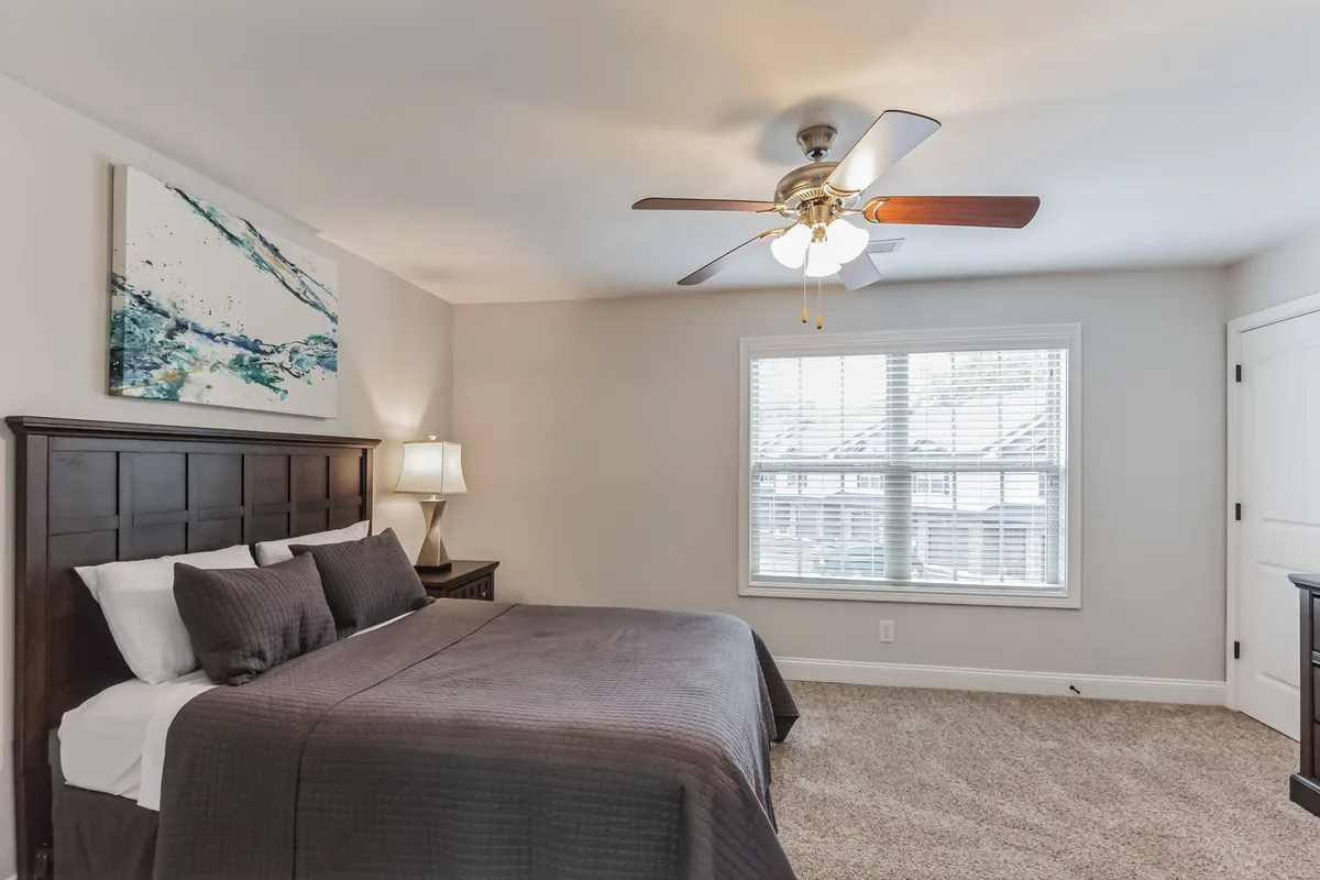 A bright bedroom with dark bedding, abstract wall art, and a window streaming in natural light. The setting is peaceful and welcoming, perfect for both morning starts and restful evenings after exploring the local area.