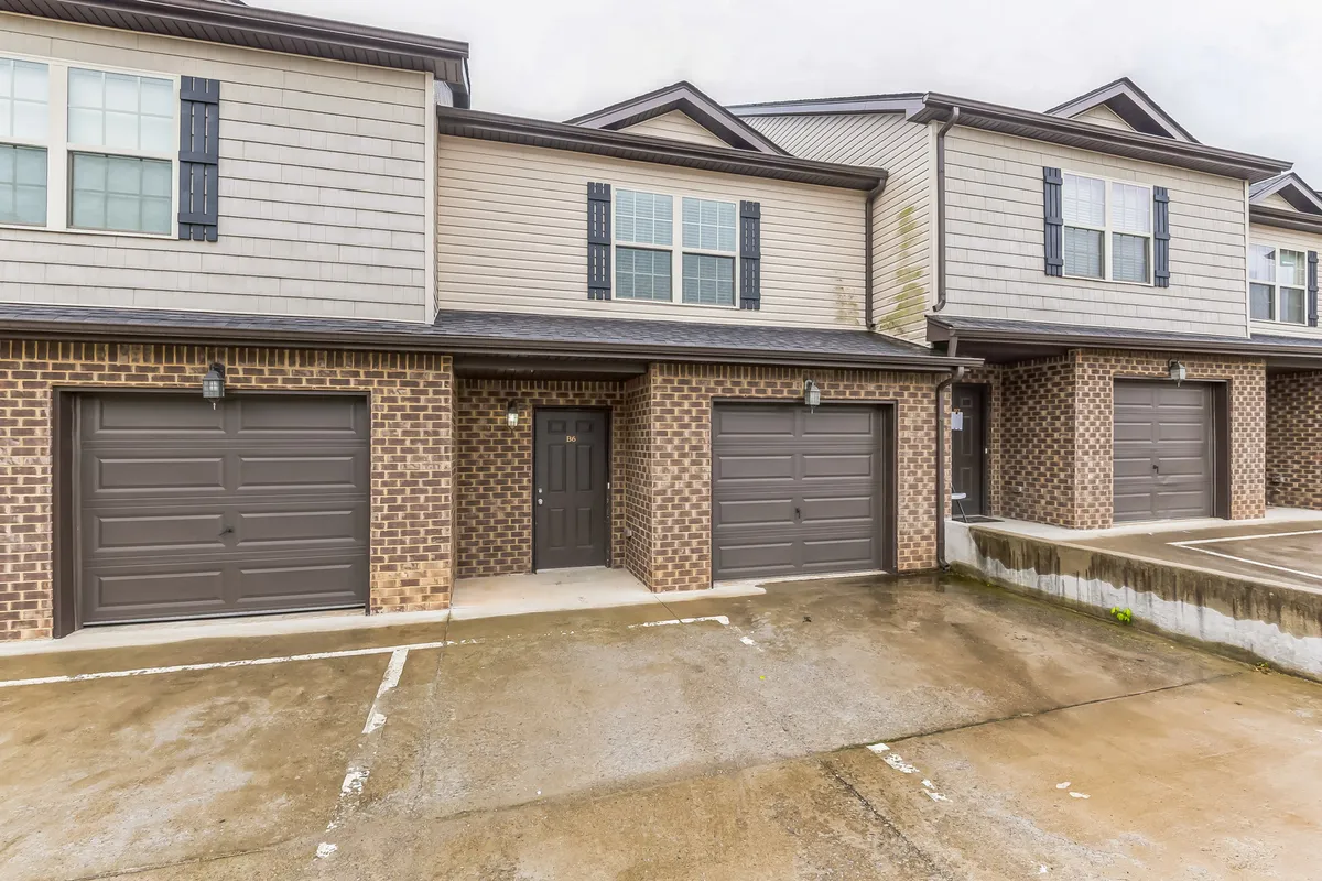 This exterior view highlights the home's private driveway, with prominent garage doors and a welcoming main entrance set against a brick facade. The driveway offers ample space for vehicles and ease of access, echoing the promise of seamless arrivals and departures.